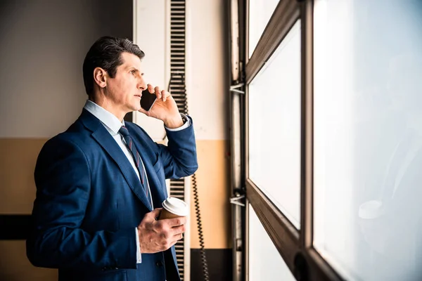 Muž s chytrým telefonem stojí na chodbě — Stock fotografie