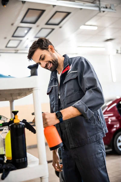 Uśmiechnięta myjka samochodowa trzymająca butelkę sprayu — Zdjęcie stockowe