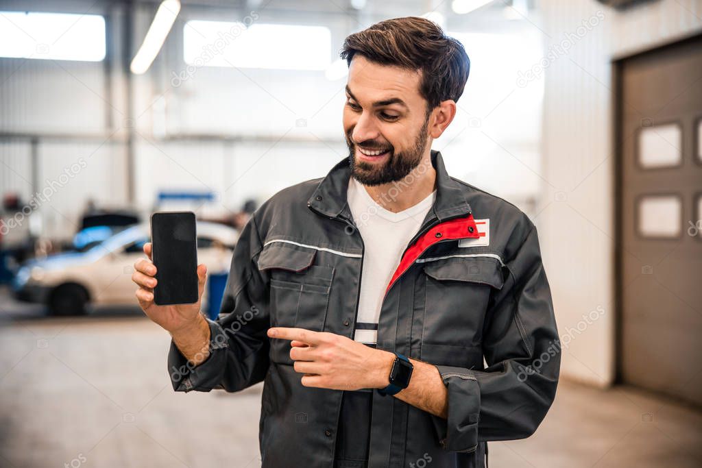 Mechanic holding a smartphone in his hand