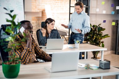 Neşeli orta yaşlı bir adam meslektaşıyla konuşuyor.