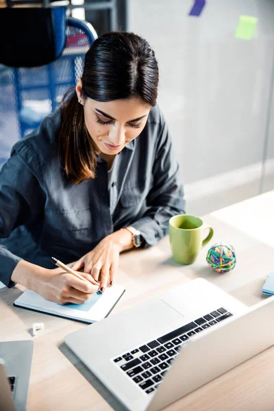 Positief verheugd jonge vrouwelijke persoon maakt notities — Stockfoto