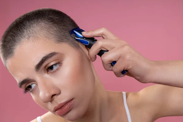 Müde junge Frau rasiert ihren Kopf Archivfoto — Stockfoto