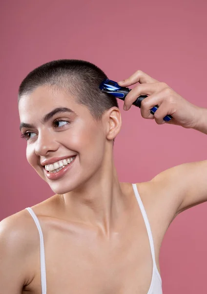 Gladsome young woman shaving her head and smiling stock photo — Stockfoto