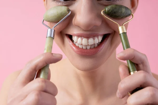 Close-up van gelukkig jong dame met behulp van jade gezicht rollers stock foto — Stockfoto