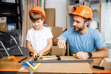 Smiling father teacing carpenter skills to son stock photo