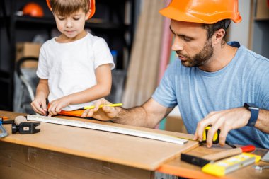 Father and son doing measurements in workshop stock photo