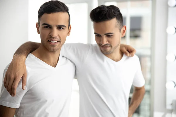 Happy twins in white t-shirts embracing in room — Stock Fotó