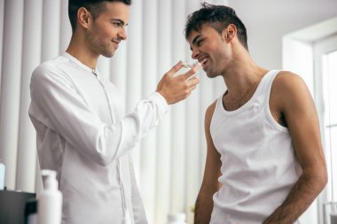 Happy young man holding perfume in room