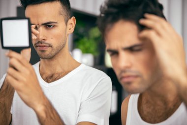 Cımbız ve ayna kullanan yakışıklı bir adam.