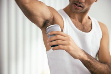 Odada deodorant kullanan tişörtlü yakışıklı adam.