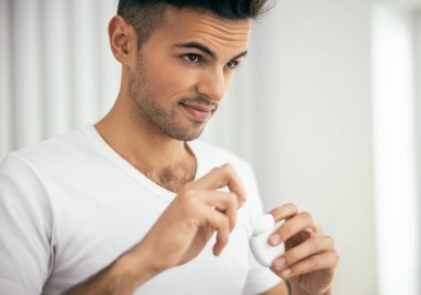 Odada diş ipi tutan gülümseyen genç adam.