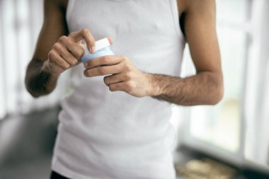 Genç adam elinde krema kavanozu tutuyor.