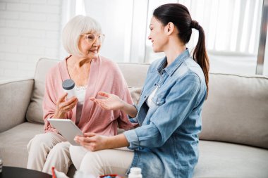 Gülümseyen doktor yaşlı bayana ilaç öneriyor.
