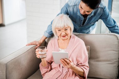 Yaşlı kadın torunuyla dijital tablette video izliyor.