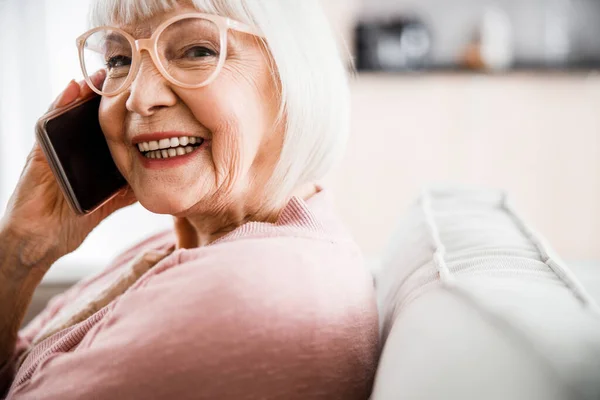 Весела стара леді в окулярах говорить на мобільному телефоні — стокове фото