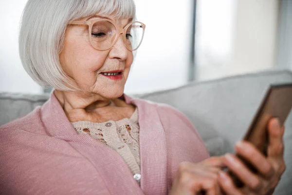 Leende gammal dam sms: ar på smartphone — Stockfoto