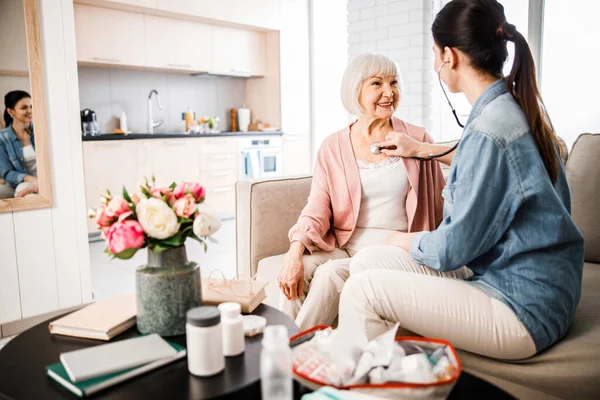 Young female doctor checking breath of senior woman — Stock Photo, Image