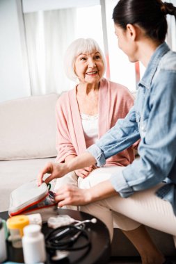 Gülümseyen yaşlı kadın aile doktoruyla konuşuyor.