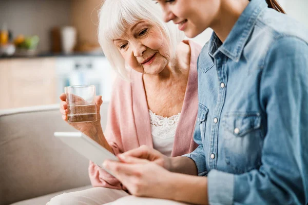 Joven dama y su abuela viendo vídeo en la tableta digital —  Fotos de Stock