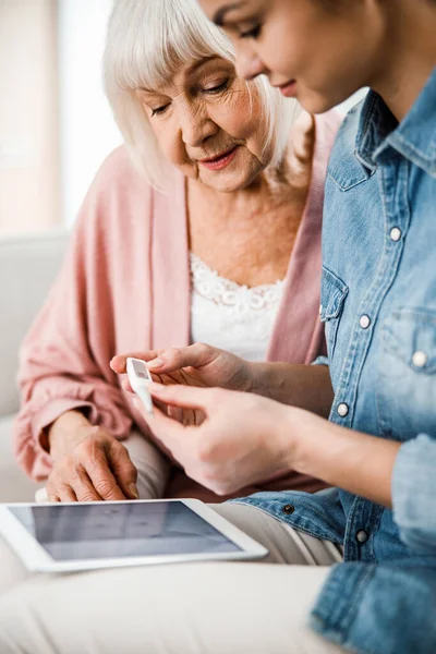 Old lady and young woman checking thermometer readings — Stock Photo, Image