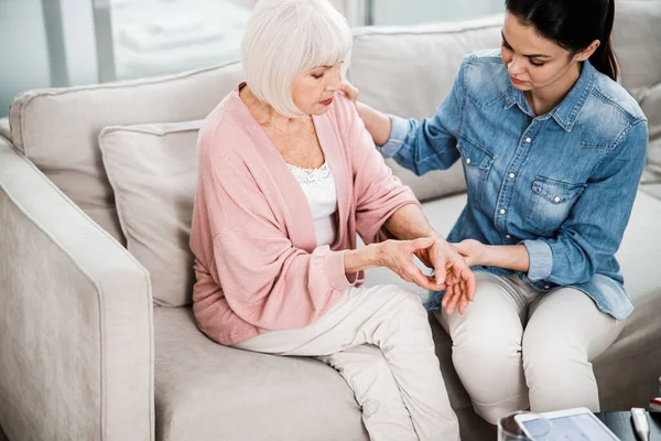 Anciana quejándose de dolor en el brazo al médico de familia — Foto de Stock