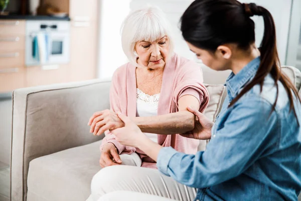 Female physician checking arm of elderly woman — Stock Photo, Image