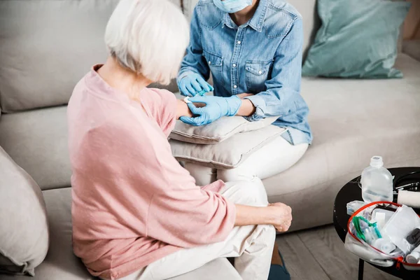 Female doctor making injection to old woman arm — Stock Photo, Image