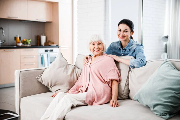 Abuela y nieta adulta mirando a la cámara y sonriendo — Foto de Stock