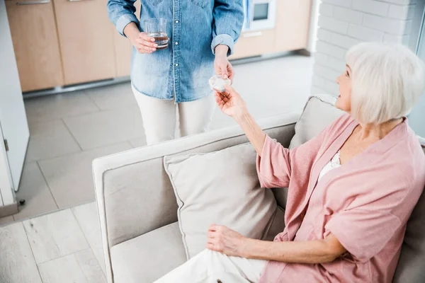 Young woman giving pills to old lady — Stock Photo, Image