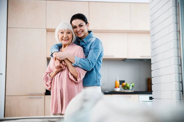 Feliz abuela y nieta adulta abrazando y sonriendo — Foto de Stock