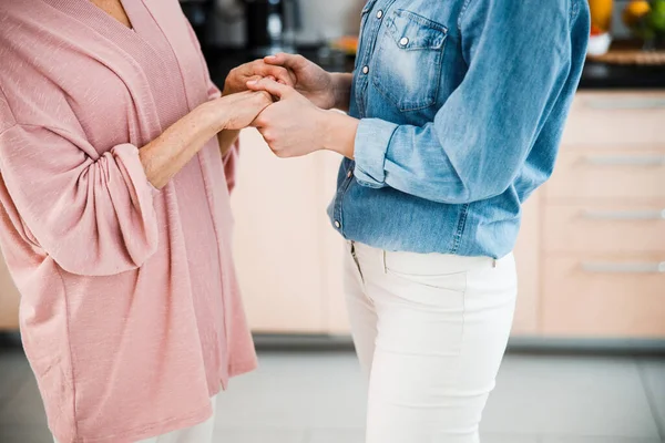 Grandmother and adult granddaughter holding hands at home — Stock Photo, Image