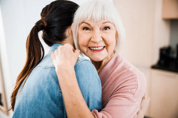 Feliz anciana abrazando a su nieta y sonriendo —  Fotos de Stock