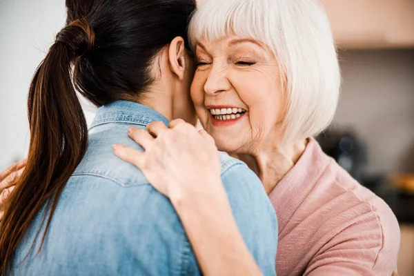 Alegre anciana abrazando a su nieta y sonriendo — Foto de Stock