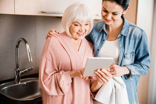 Grandmother and adult granddaughter using modern gadget at home — Stock Photo, Image