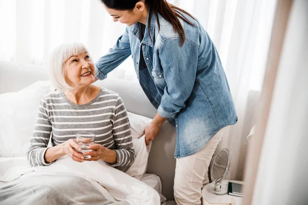 Loving granddaughter taking care of grandmother in bedroom — Stock Photo, Image