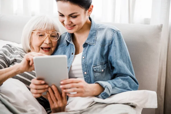 Alegre anciana y su nieta usando moderno gadget —  Fotos de Stock