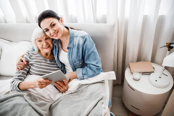 Gelukkig oud vrouw en haar kleindochter knuffelen in slaapkamer — Stockfoto