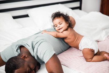 Father and cute newborn daughter taking nap at home clipart