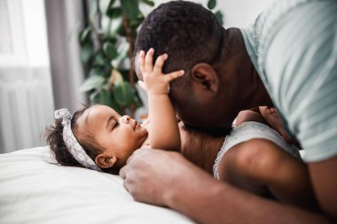 Afro Amerikalı adam yeni doğmuş tatlı kızının göbeğini öpüyor.