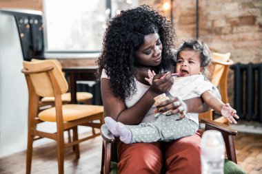 Afro Amerikalı kadın kaşıkla besliyor tapılası bebeği