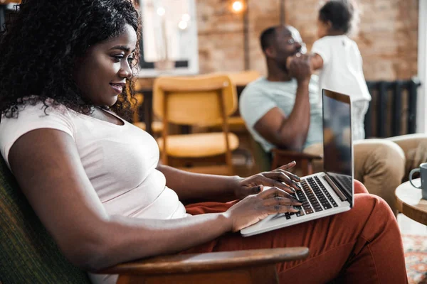 Афроамериканка, яка користується ноутбуком вдома. — стокове фото