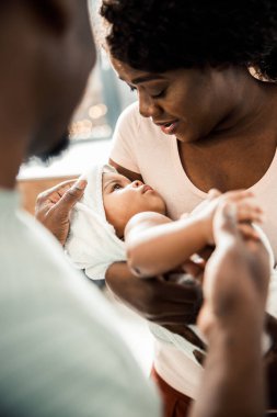 Çekici Afro-Amerikalı kadın kucağında bebeği tutuyor.