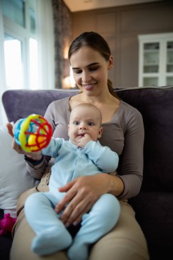 Küçük bebeğiyle kanepede oynayan güzel genç bir anne.