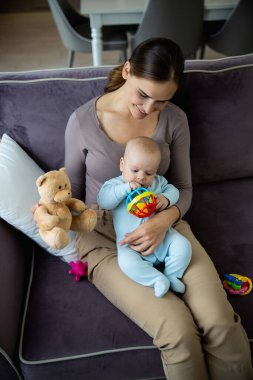Evinde oynayan sevimli çocuğuyla mutlu güzel bir kadın.
