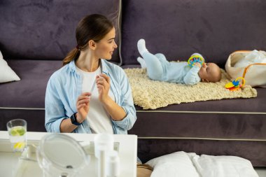 Gülümseyen güzel bayan odada bebeğine bakıyor.