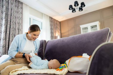 Gülümseyen kadın ve tatlı çocuk oturma odasında kanepede oynuyorlar.