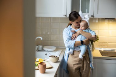 Gülümseyen genç bir kadın sabahları bebekle eğleniyor.