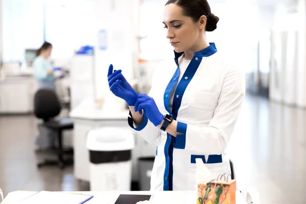 Όμορφη νεαρή κοπέλα στο εργαστήριο που φοράει μπλε αποστειρωμένα γάντια — Φωτογραφία Αρχείου