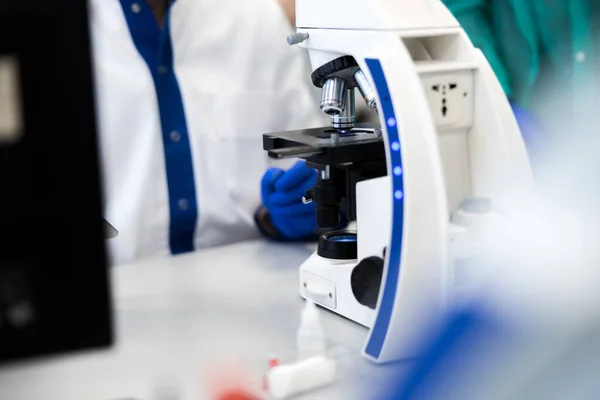 Man wetenschapper zit aan de tafel met moderne microscoop — Stockfoto