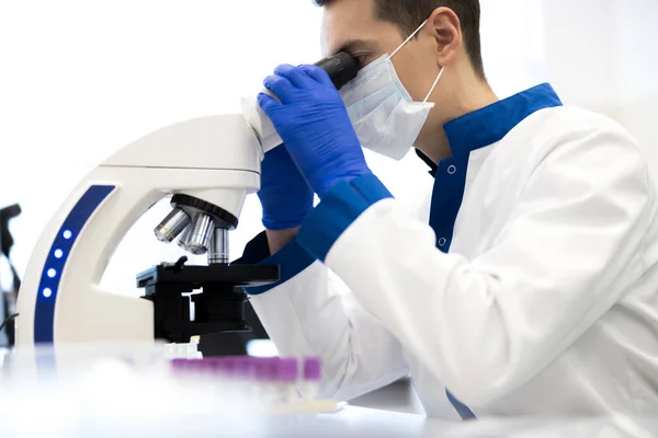 Joven investigador masculino usando microscopio en laboratorio de ciencias — Foto de Stock